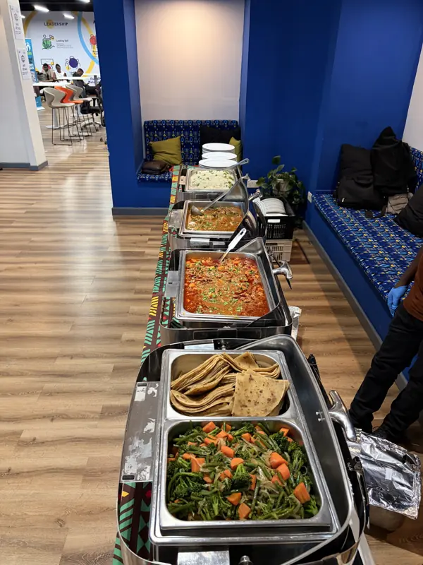 A hot lunch buffet with chafing dishes and a colourful African print runner