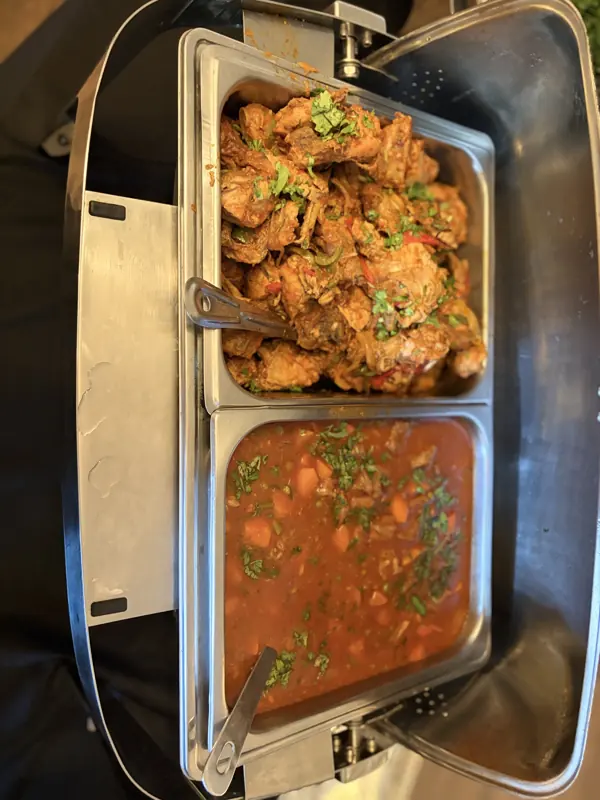 Chicken and a rich stew served hot in a chafing dish